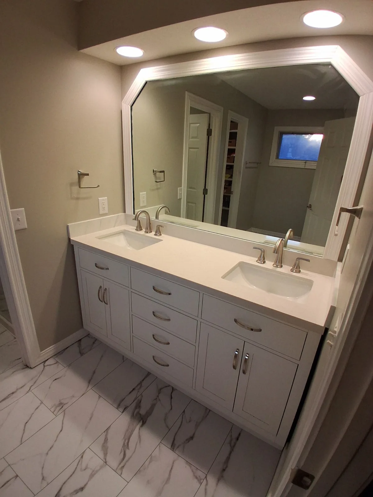 Finished double-sink vanity with white cabinetry and marble-look floor tile